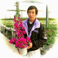 花の鉢植えを持った前川 茂さんの写真