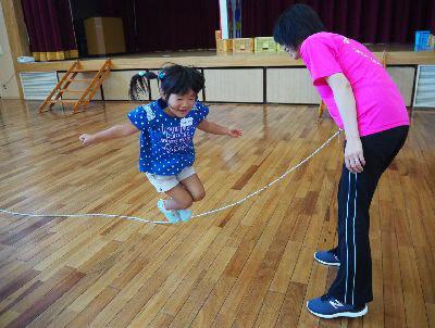 スタッフの方が回している縄跳びをジャンプしている女の子の写真