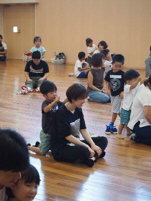 床の上に座っている保護者の肩をたたいている子供たちの写真