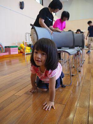 椅子で作られたトンネルを女の子が四つん這いになって出てきている写真
