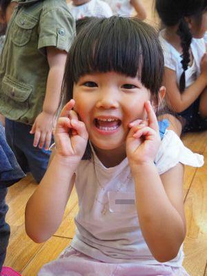 女の子が両手で顔の横にピースサインをしている写真