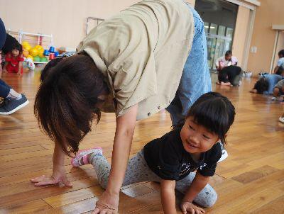 お母さんが手を床につけて体でトンネルを作っていて、その間を子供がくぐり抜けている写真