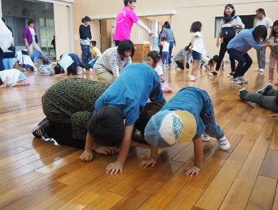 子ども二人が床に手をつけてトンネルを作っていてその間をお母さんが小さくなってくぐろうとしている写真