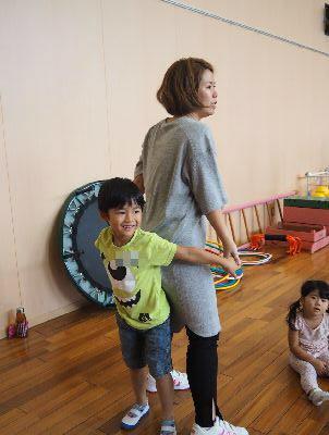 お母さんと男の子が背中合わせに立って、両手をつないでいる写真