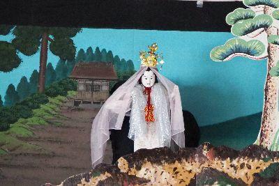 金色の冠を頭に乗せ白い衣装を着ている人形の写真