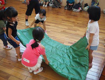 緑の体育マットを女の子4人で運んでいる写真