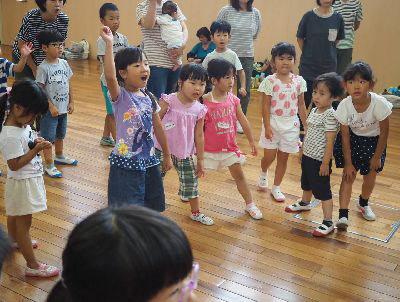子ども達が集まって立っており、中央の紫色のティーシャツを着た女の子が「おー!」と声を挙げて右手を上に挙げている写真