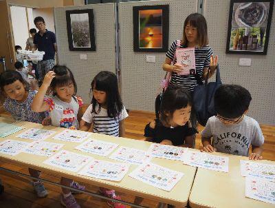 机の上に出席カードが並べられており、子ども達が机の前に並んでカードを見ている写真