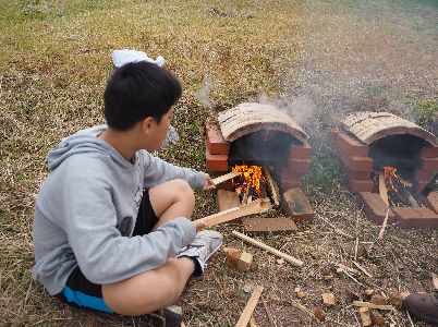 石窯に木をくべる子ども