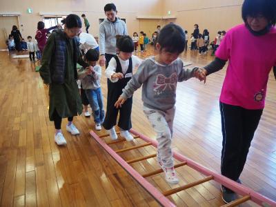 手をそえられてはしごを渡る子ども