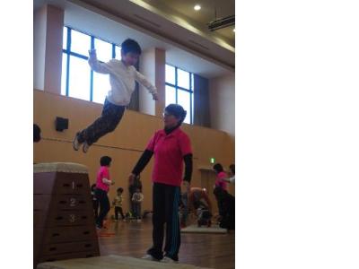 跳び箱から飛び降りる子どもとそれを見守るスタッフ