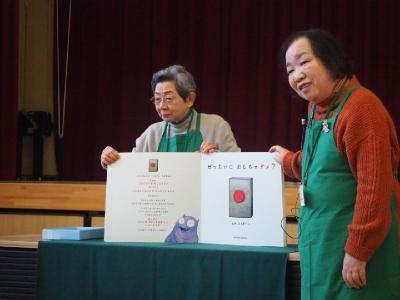 大きな絵本を広げ絵本の読み聞かせをしている