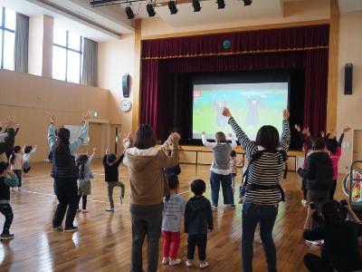 スクリーンを見ながら踊る大勢の親子