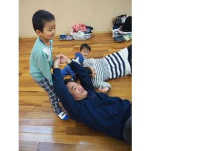 お父さんを持ち上げようと頑張っている子ども