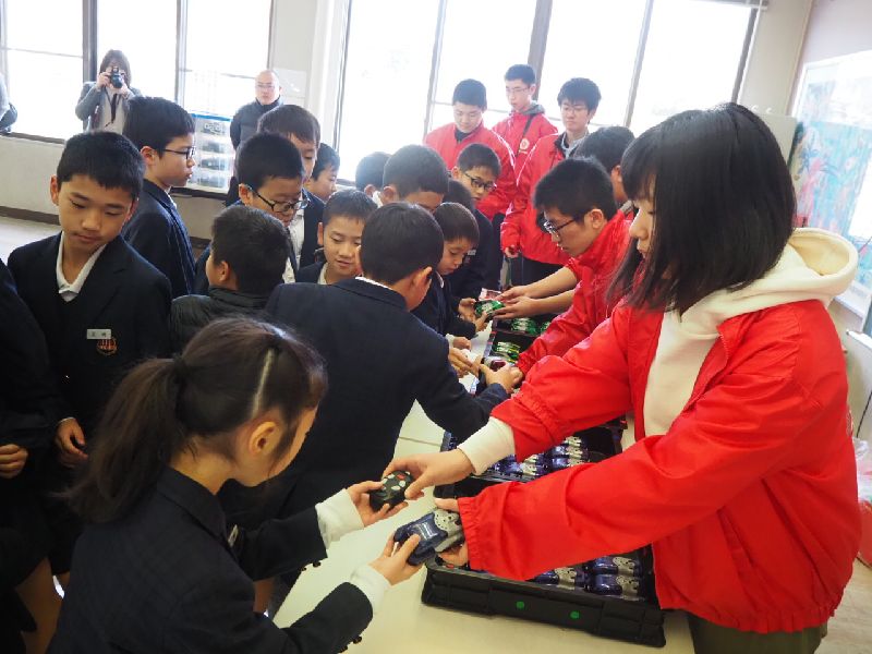 香川高専の生徒から機材を手渡ししてもらう子どもたち