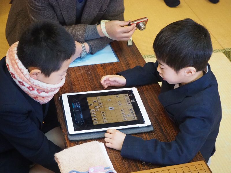 タブレットのアプリで将棋をさす子どもたち