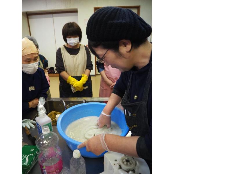 たらいに移したこんにゃく芋を手でかき混ぜる講師