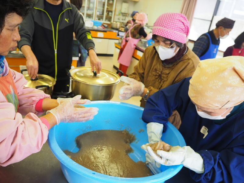 たらいのなかの少し固まった材料を手で丸く形成する参加者