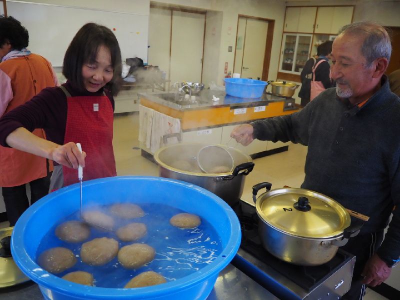 茹であがったこんにゃく玉を網ですくい水をはったたらいにうつしている