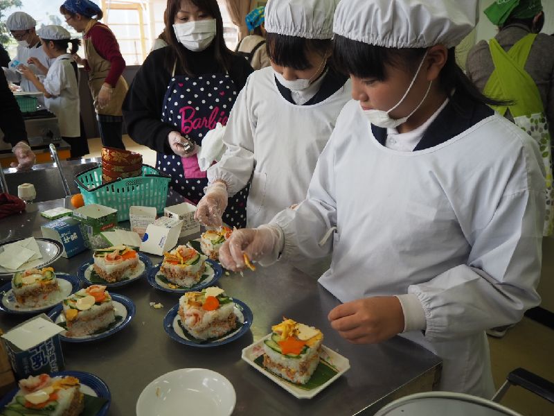 ちらし寿司に具材をのせる子どもたち