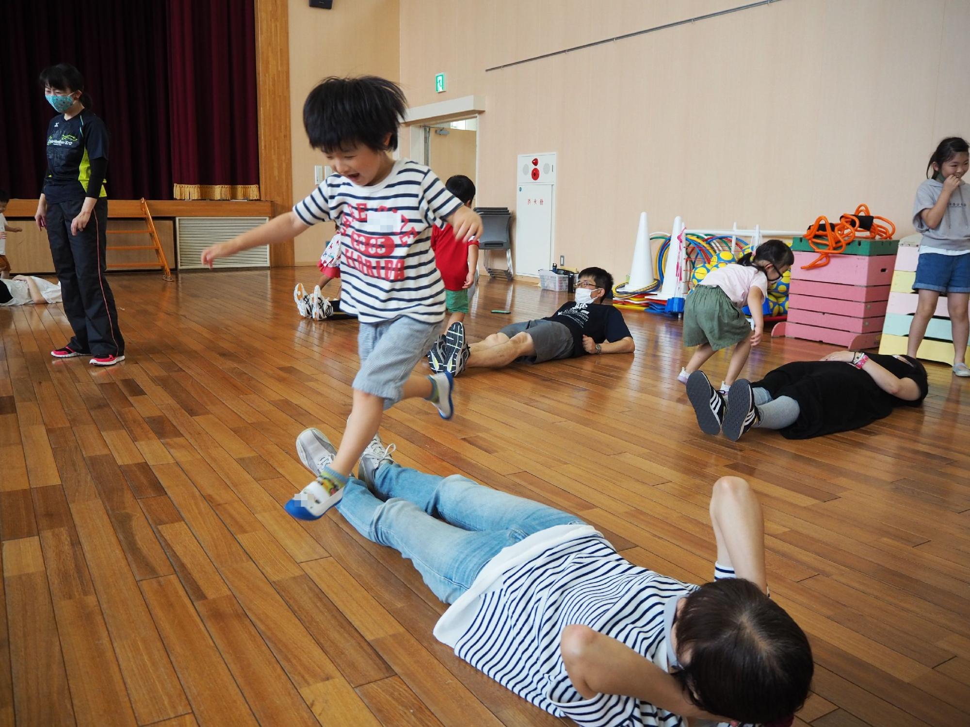 保護者の足の上を飛び越える子ども