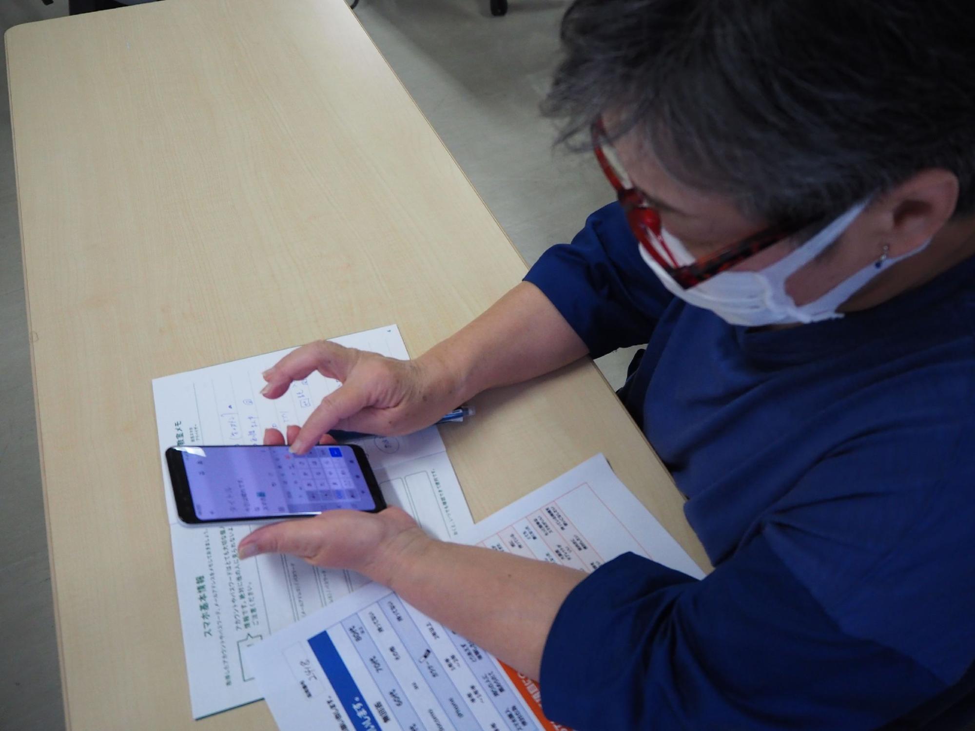 貸し出されたスマホを操作する受講生