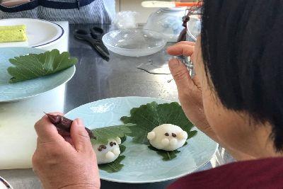 女性がチョコペンで柏餅のゴマちゃんに目を描いている写真