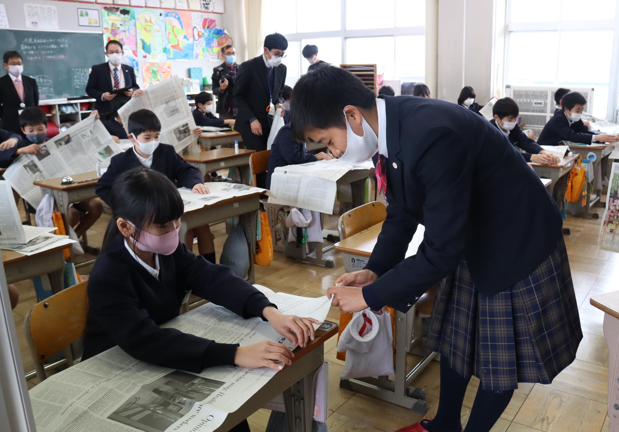 四学香川西校の生徒と勝間小学校の児童が協力して新聞紙でエコバッグを作っています。