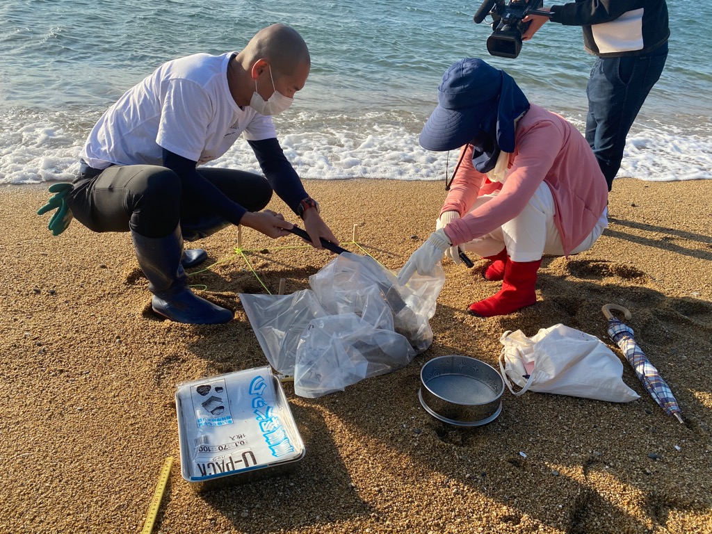 砂浜の砂などを採取する研究員たち