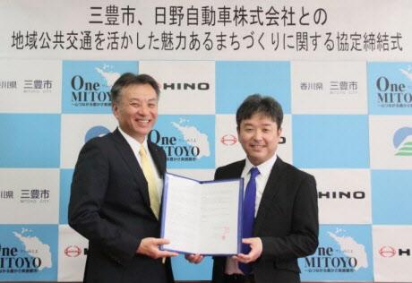 市長と日野自動車株式会社の代表の方が二人で協定書を持って立っている写真