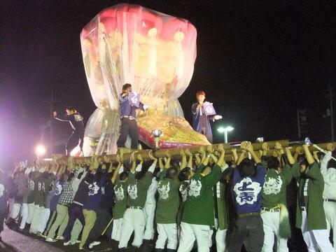 本山太鼓まつりにて黄金の獅子舞の神輿が担がれており、男性が神輿の上に立っている写真