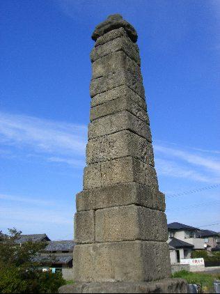 異形十三重層の石の塔が青空に向かって立っている写真