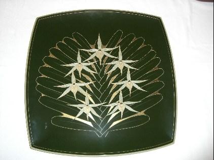 深緑色を基調とした四角の皿に白色で花の絵が描かれている写真