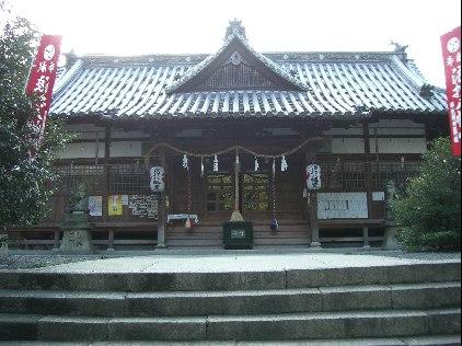 茶色の壁の上に瓦屋根のある神社の建物の写真