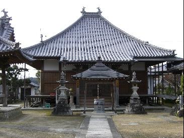 中央に神社の建物へと続く道があり建物の正面に賽銭箱のようなものが置かれてある写真