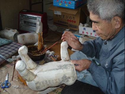 真鍋 佳則さんが虎の胴体に足を付ける作業をしている写真