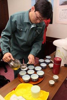 男性がお茶を湯飲み茶わんに入れている写真