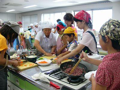調理室でたくさんの子供と大人が一緒に料理をしている写真