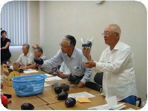 会議室で三豊ナスを手に取り話し合いをしている三豊ナス研究会会員の写真