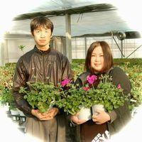 花の鉢植えを両手に持った直人さん美妃さんご夫婦の写真