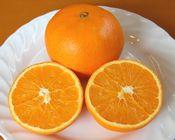 1個と半分に切ったネーブルオレンジがお皿に乗せられている写真