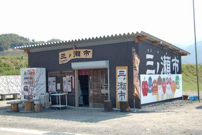 三ノ瀬市の看板が掲げられ、黒い外壁に野菜のイラストが描かれた建物の外観写真