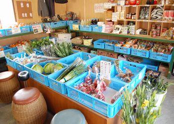 野菜や果物などが入った青いケースが並んだ店内の写真
