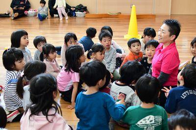 女性スタッフの周りに子供たちが集まって話を聞いている写真