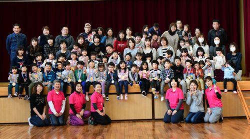 舞台の上に参加者の親子たちが座っていて、舞台の前にスタッフが並んでいる集合写真