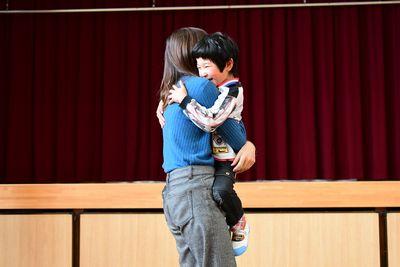 小さな男の子がお母さんに抱きかかえられている写真