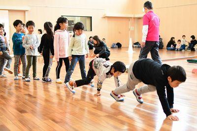 縦に並んだ子供たちが順番に四つん這いになって歩いている写真