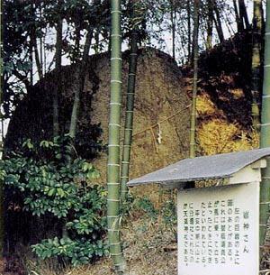 竹藪の中に巨大な石が祀ってあり岩神さんとかかれた案内看板がある写真