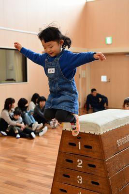 跳び箱の上から女の子がジャンプして飛び降りている写真