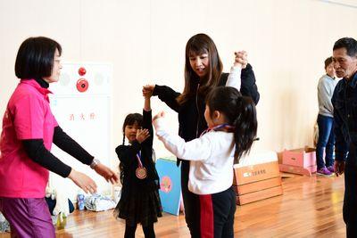 お母さんが両脇にいる女の子2人と手をつないでいて、つないだ手を高く上げている写真